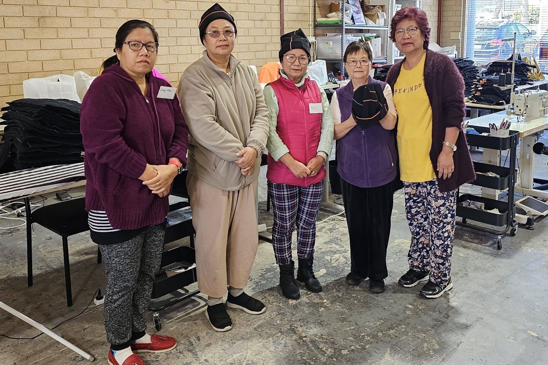 Picture of Loop upcycling participants holding beanies made from 7-Eleven uniforms