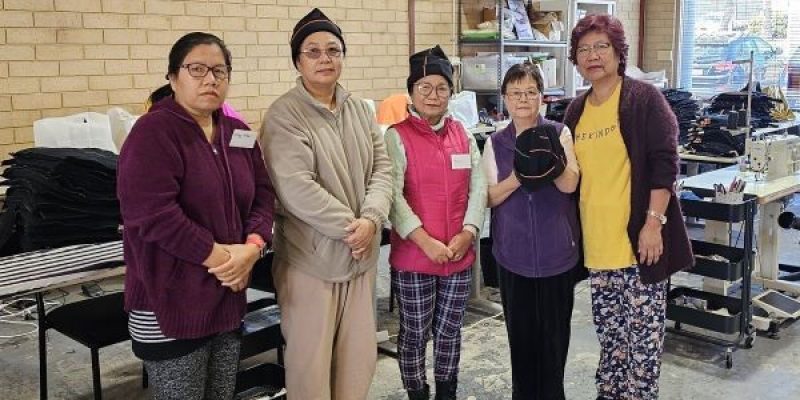 A picture of Loop Upcycling participants, holding beanies made from old 7-Eleven uniforms.